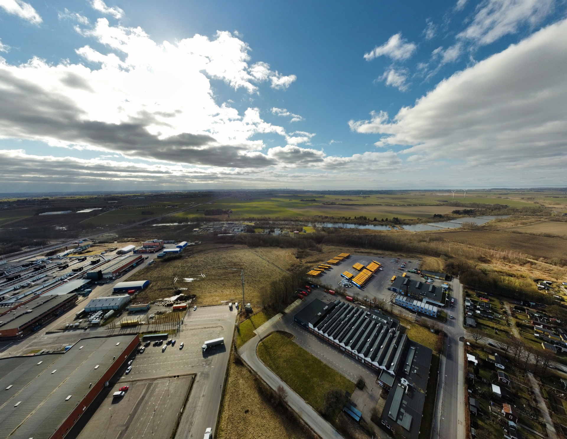 Vidsträckt landskap med industriområde och åkrar